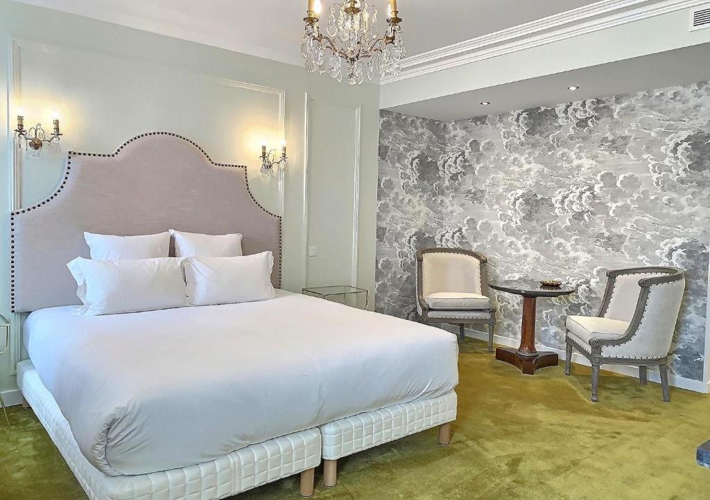 a bedroom with a large white bed and two chairs at Le Tardif, Noble Guesthouse in Bayeux