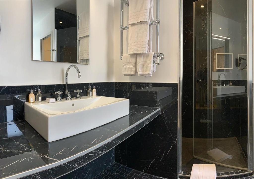a bathroom with a white sink and a shower at Le Tardif, Noble Guesthouse in Bayeux