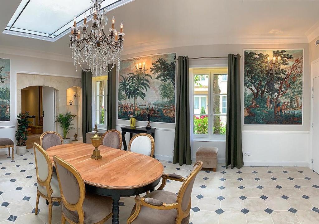 a dining room with a table and chairs and a chandelier at Le Tardif, Noble Guesthouse in Bayeux