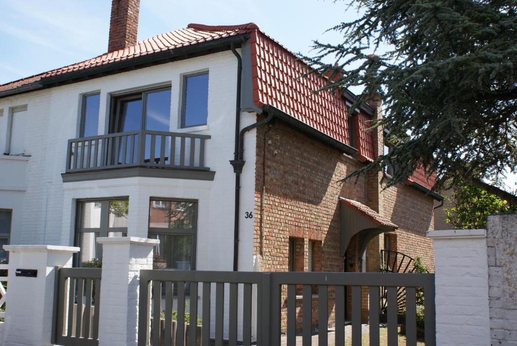 a white house with a fence in front of it at Belle Villa in De Panne