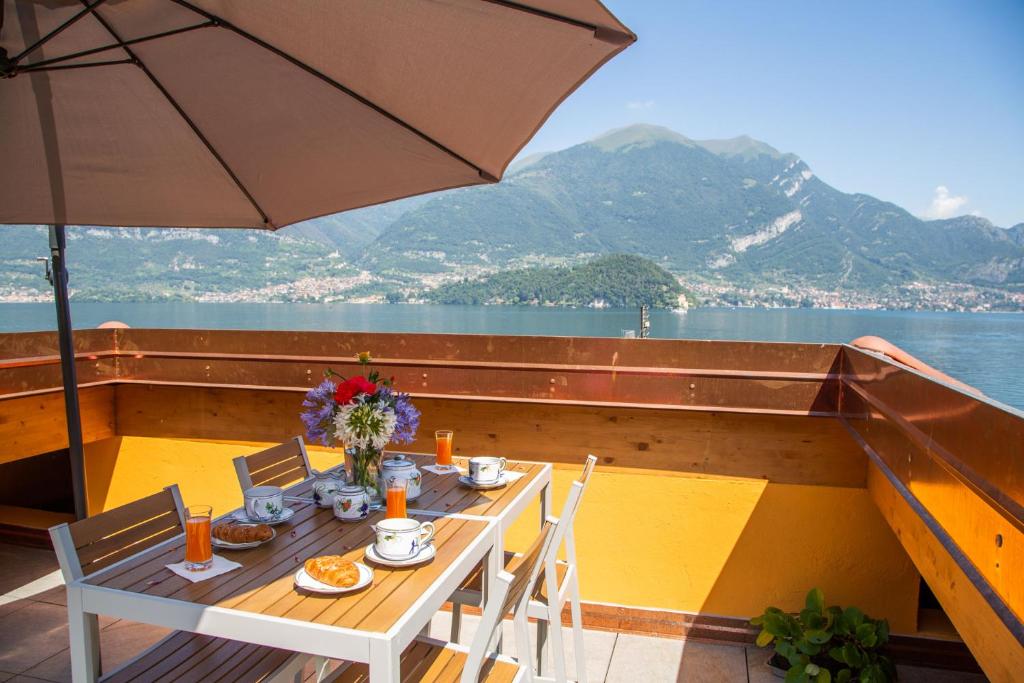 a table and chairs on a boat with an umbrella at La Terrazza sul lago Lezzeno in Lezzeno
