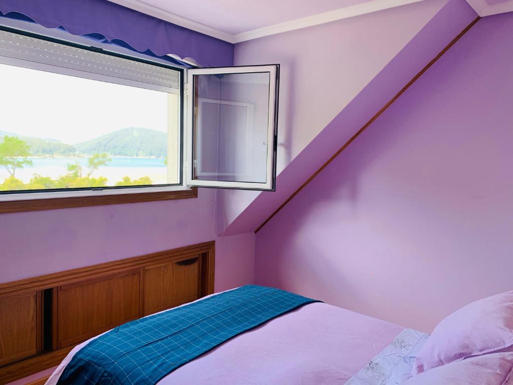 Habitación púrpura con cama y ventana en Ático en primera línea de playa en Cedeira