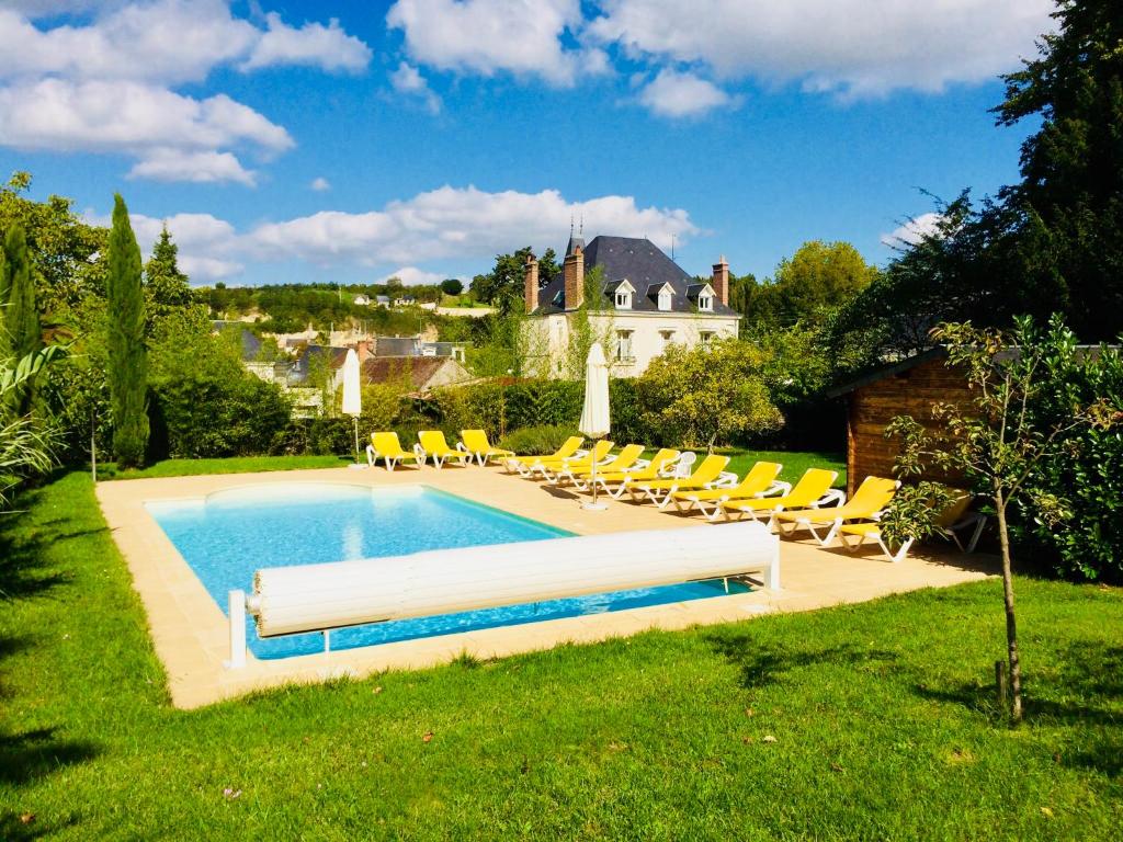 a swimming pool in a yard with chairs and a house at Manoir Du Parc (Adults only) in Amboise