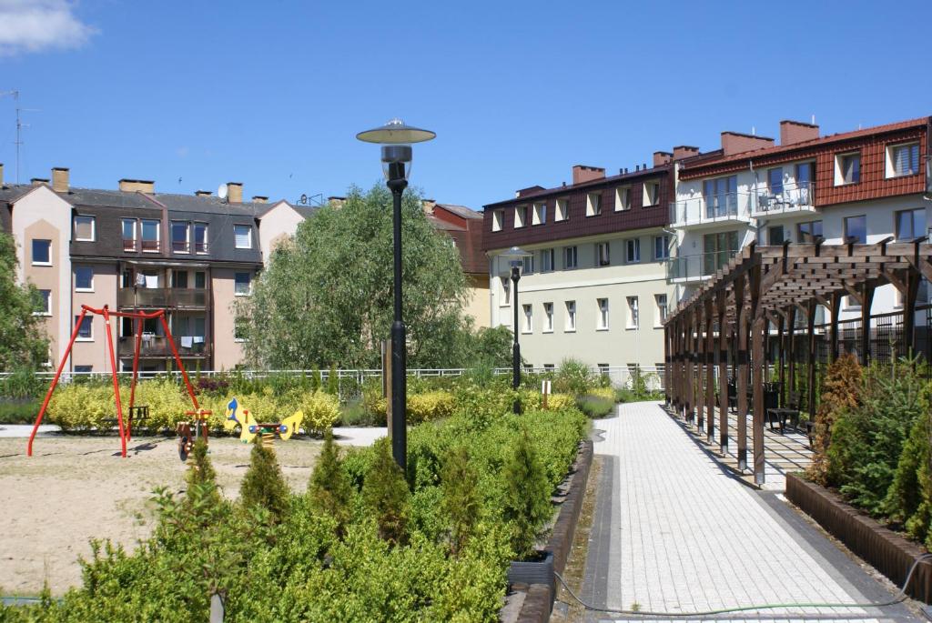 un jardin avec une aire de jeux et des bâtiments en arrière-plan dans l'établissement Apartamenty Bryza - Kwartał Róży Wiatrów, à Świnoujście