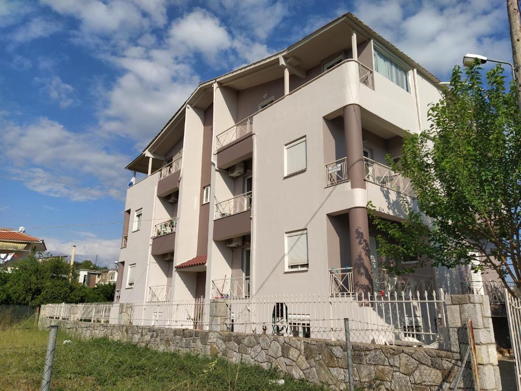 a white building with a fence in front of it at Fotini Apartments in Andikálamos