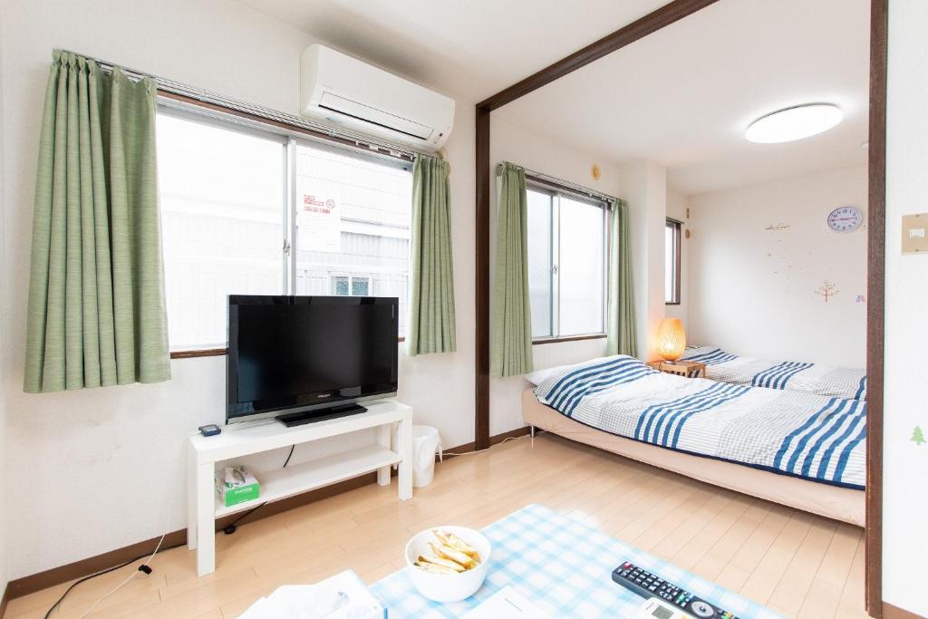 松戶的住宿－松戸 テイクファイブ 1DK Nomad松戸宿056，一间卧室配有一张床和一张桌子上的电视