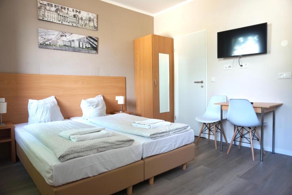 Schlafzimmer mit einem Bett, einem Schreibtisch und einem TV in der Unterkunft Apartment Hotel Wittenau in Berlin