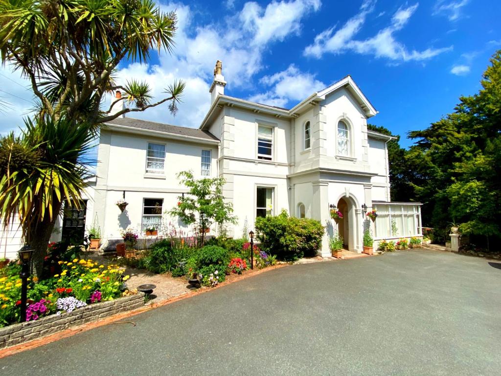 a white house with a palm tree and a driveway at Muntham Luxury Holiday Apartments in Torquay