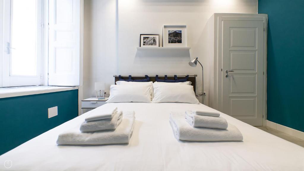 una camera da letto con un grande letto bianco con due asciugamani di B&B A' Casarella a Napoli