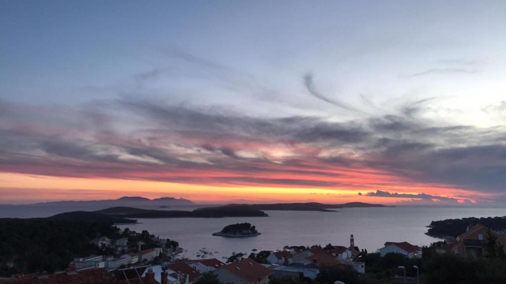 una puesta de sol sobre una ciudad con un barco en el agua en Apartmani Anka Hvar, en Hvar