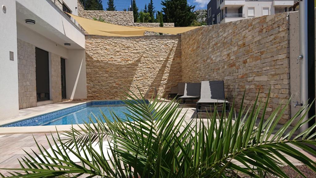 einen Pool mit zwei Stühlen und einer Ziegelwand in der Unterkunft Villa Horizon in Starigrad-Paklenica