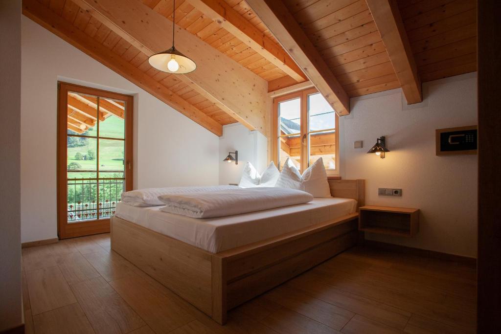 een slaapkamer met een bed en een groot raam bij Peil HighEnd-Basic apartments in San Candido