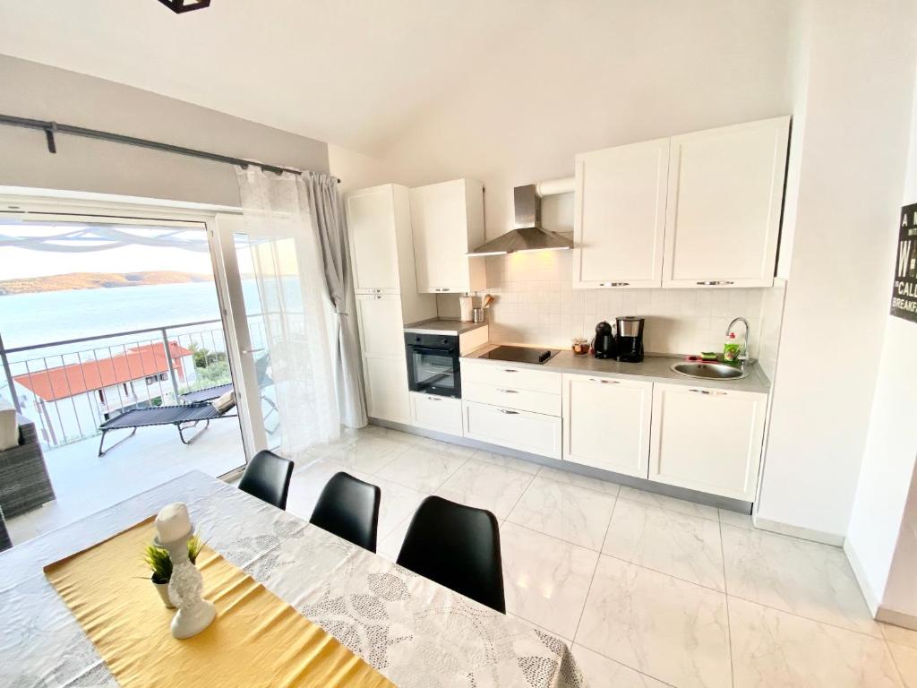 une cuisine avec des placards blancs et une table avec des chaises dans l'établissement Apartment Larum, à Zavala