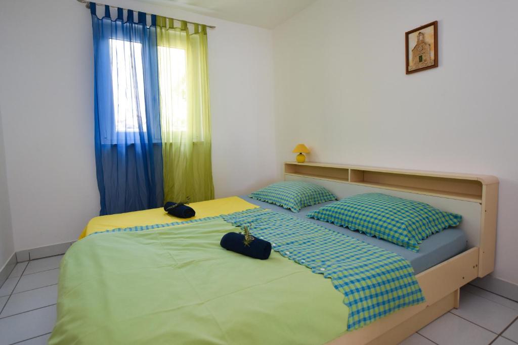 two beds in a bedroom with blue and green at Apartman Rosa 2 in Kustići