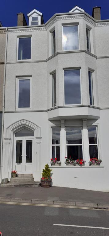 a white house with windows and flowers on a street at Mervue Apartment, 4 Causeway View, Portrush in Portrush