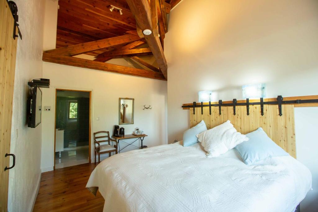 a bedroom with a large white bed and wooden ceilings at Domaine de Terrac in Rimont