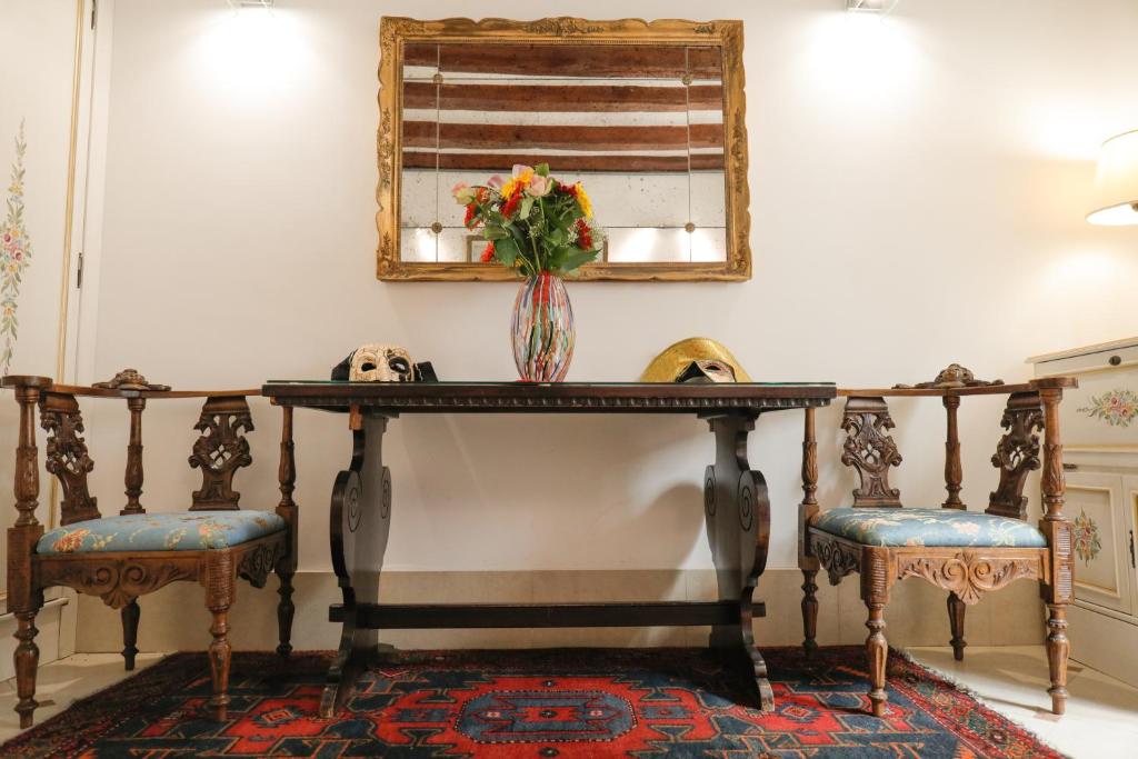 a table with a vase of flowers on it with two chairs at Casa Vacanze Angolo 'Sconto in Venice