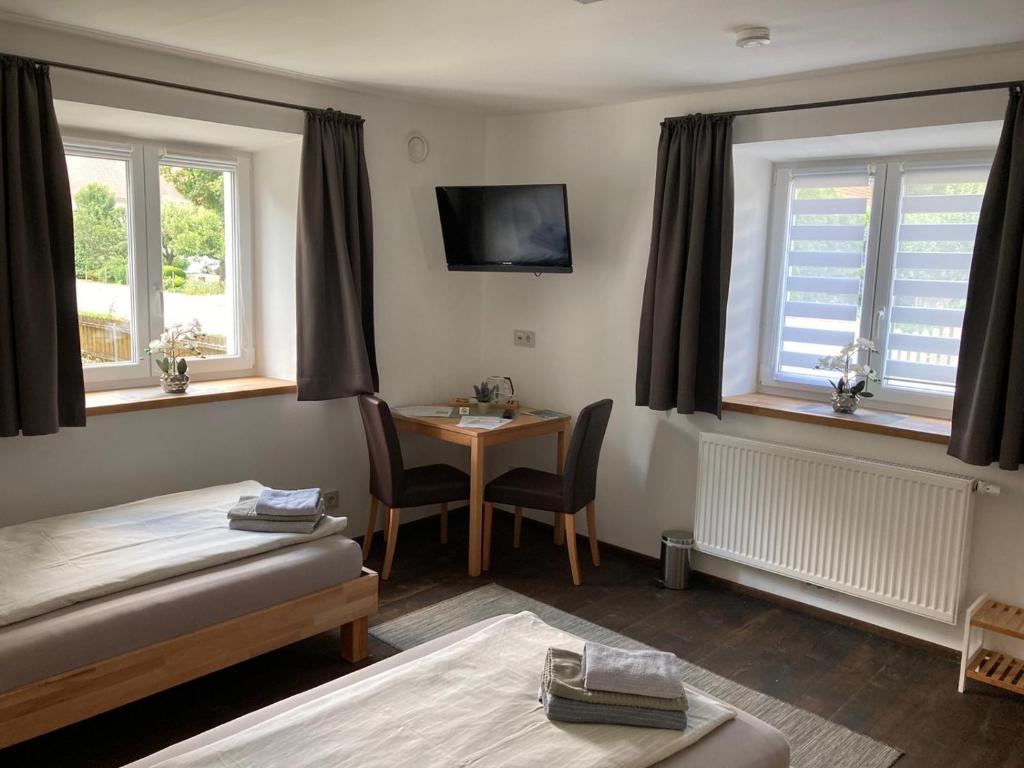 a room with a bed and a table and windows at Pension Zur Alten Post in Untermeitingen