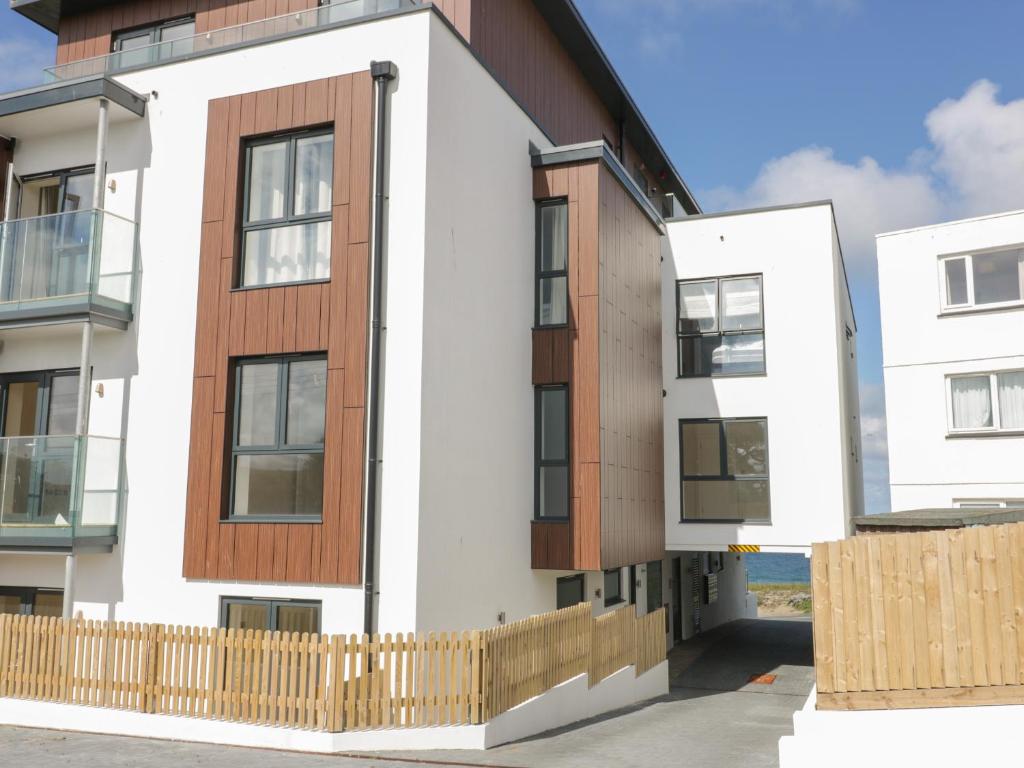 une maison blanche avec une clôture en bois devant elle dans l'établissement Watergate View, à Newquay