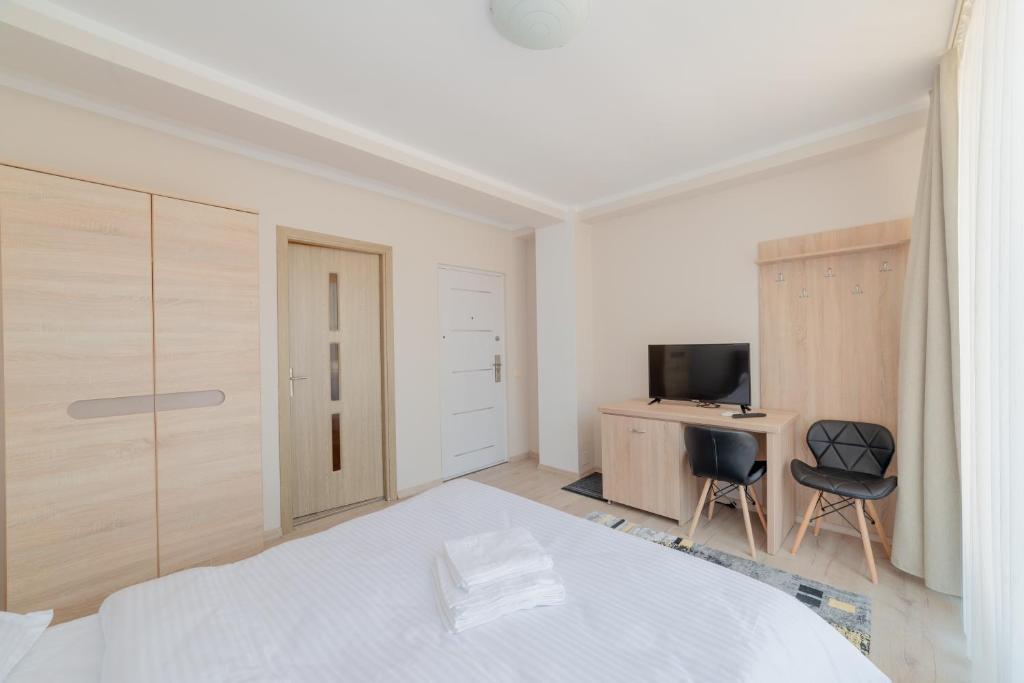 a white bedroom with a bed and a television at Casa Zorilor Cluj in Cluj-Napoca