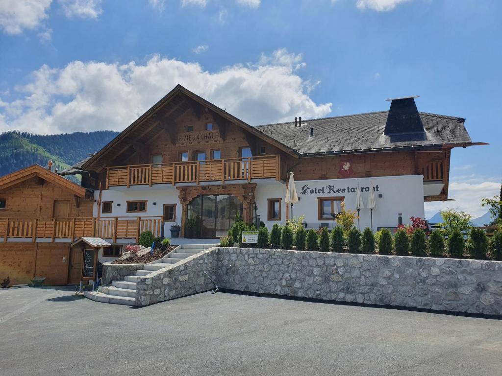 ein großes Holzgebäude mit einer Steinmauer davor in der Unterkunft Le Vieux Chalet in Crésuz