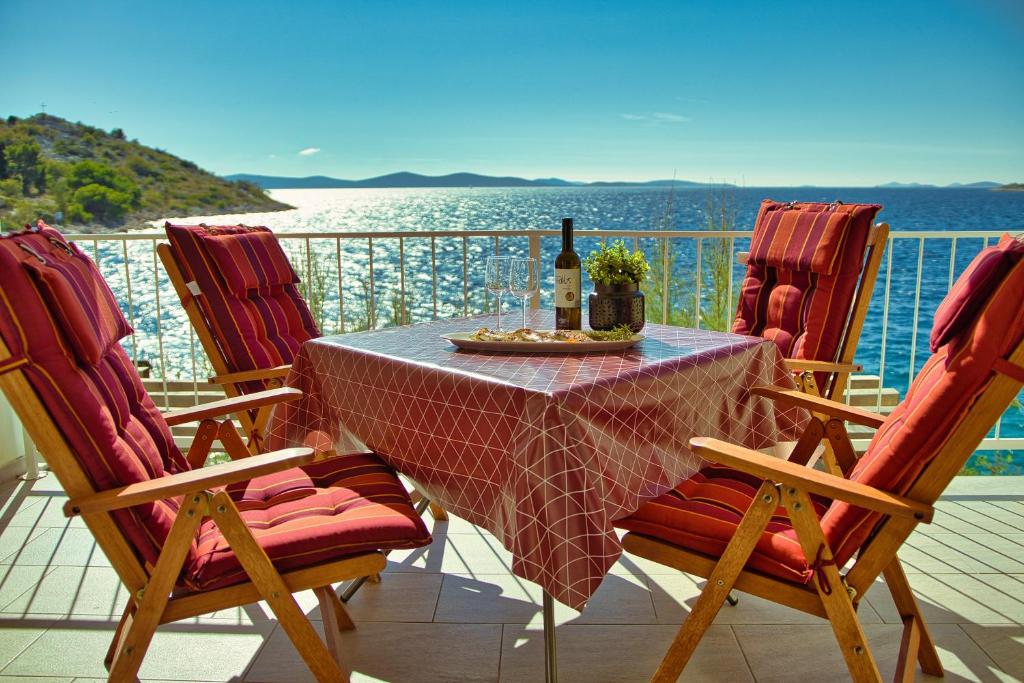 una mesa y sillas con una botella de vino en el balcón en Apartments Podvorac, en Tribunj