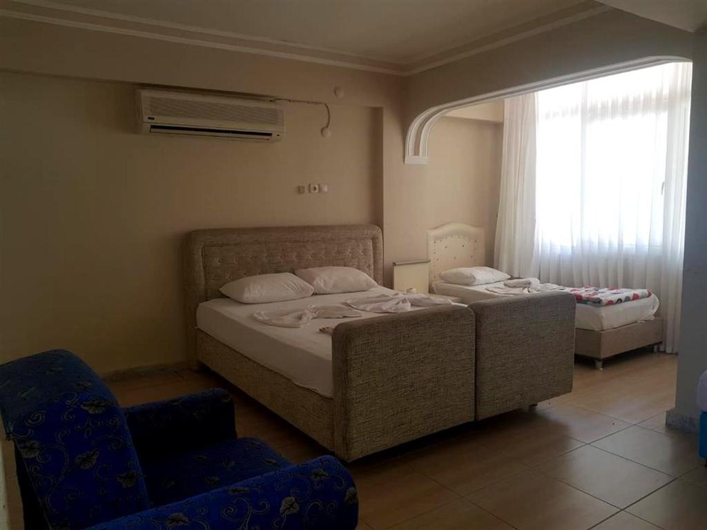 a bedroom with two beds and a chair and a window at Selina Hotel in Kusadası