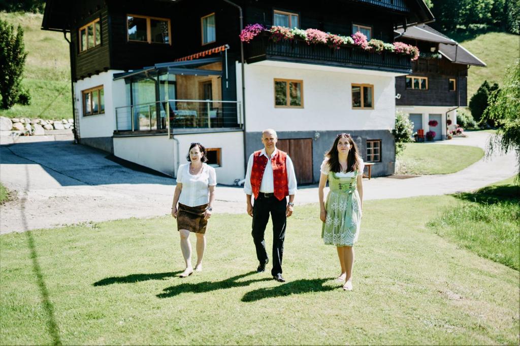 three people walking in front of a house at Appartement VIDMAR-FERIENGLÜCK in Arriach