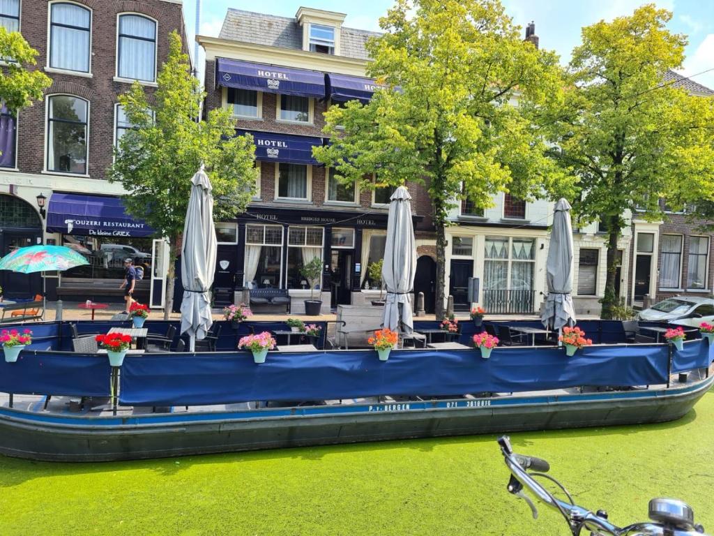 a blue boat with umbrellas on a river at Hotel Bridges House - Delft City Centre in Delft