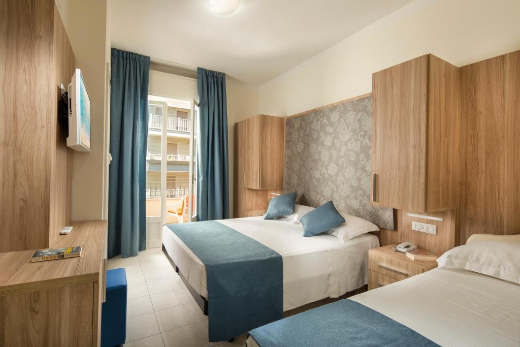 um quarto de hotel com duas camas e uma janela em Hotel Cannes - in pieno centro em Riccione