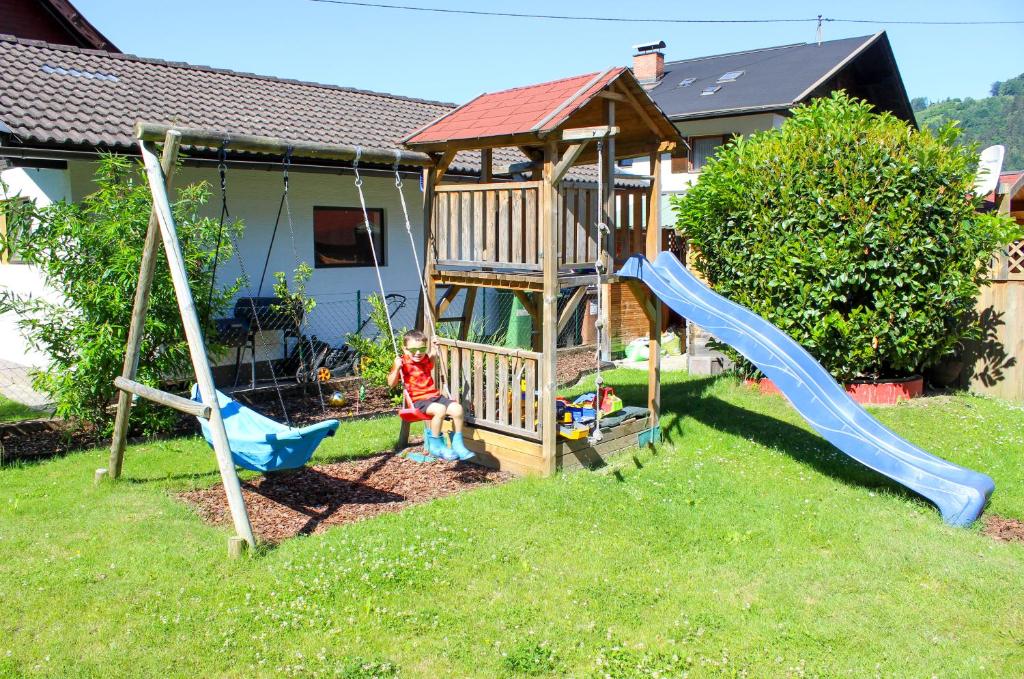 un bambino seduto su un'altalena in un parco giochi di Pension Lärchenhof a Döbriach