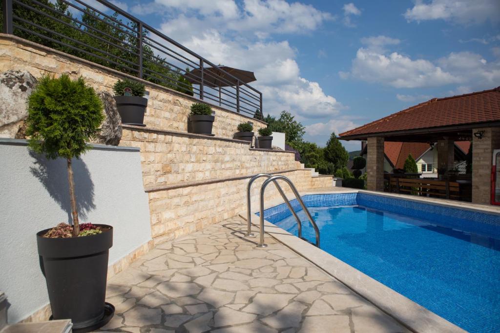 a swimming pool with a potted plant next to a house at Apartment Mario in Otočac