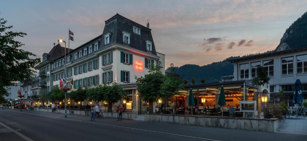 een gebouw in een straat waar mensen over straat lopen bij Hotel Krebs Interlaken in Interlaken