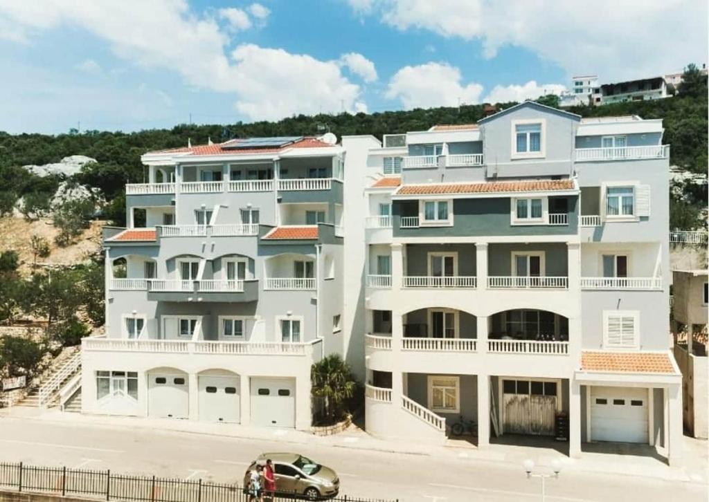 un gran edificio blanco con un coche aparcado delante de él en Hotel Luna, en Neum