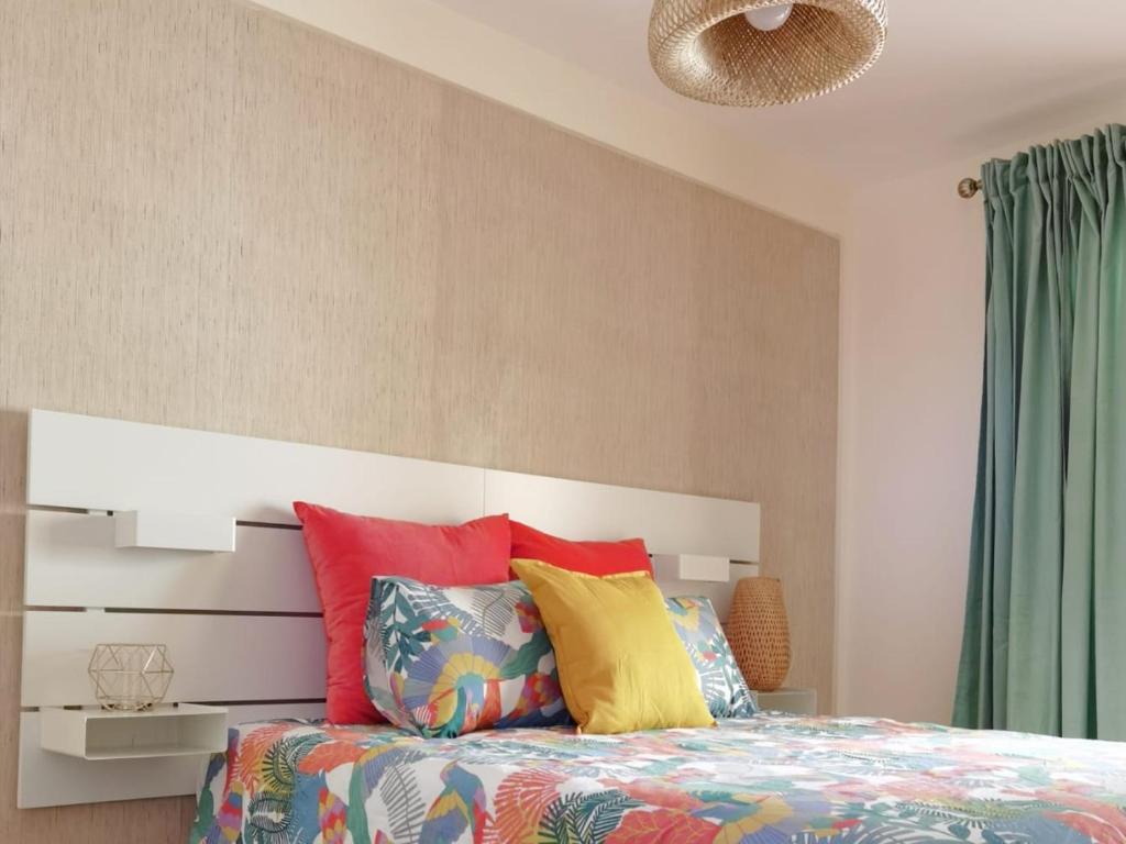 a bedroom with a bed with colorful pillows at Nautilus I: Casa con terraza y vistas al mar in La Caleta