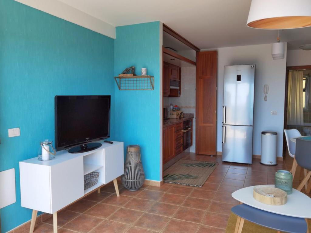 a living room with a television and a blue wall at Nautilus I: Casa con terraza y vistas al mar in La Caleta