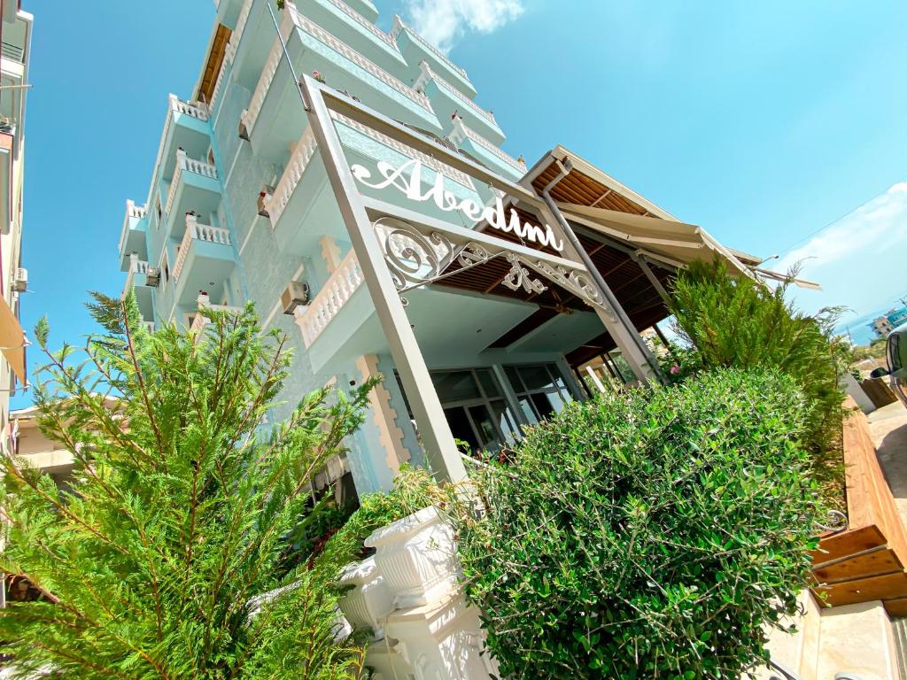 un edificio azul con arbustos delante de él en Hotel Abedini, en Sarandë