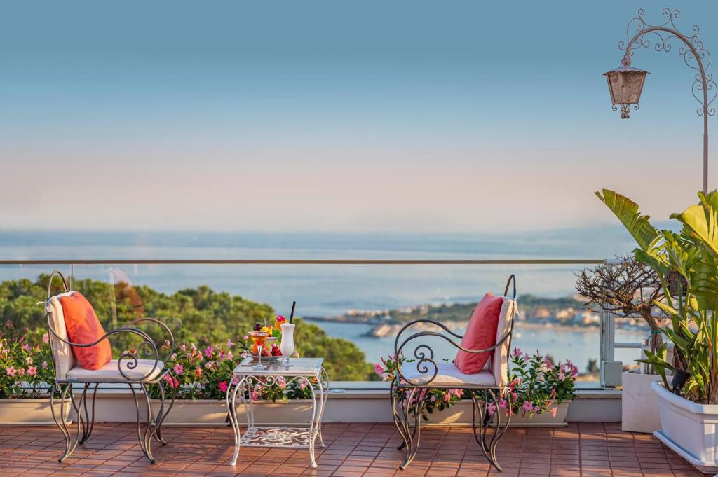 2 Stühle und ein Tisch auf einem Balkon mit Aussicht in der Unterkunft Hotel Continental in Taormina