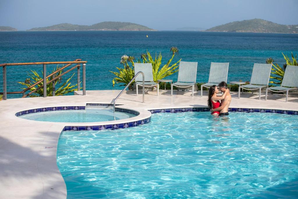 a woman sitting in a swimming pool next to the ocean at Gallows Point Resort in Saint John