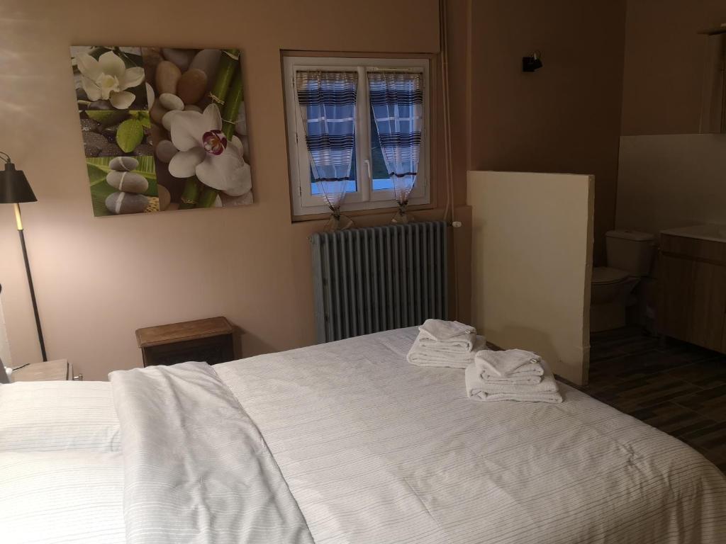 Un dormitorio con una cama blanca con toallas. en Ô Vents d'Anges - Maison d'hôtes, en Maurens
