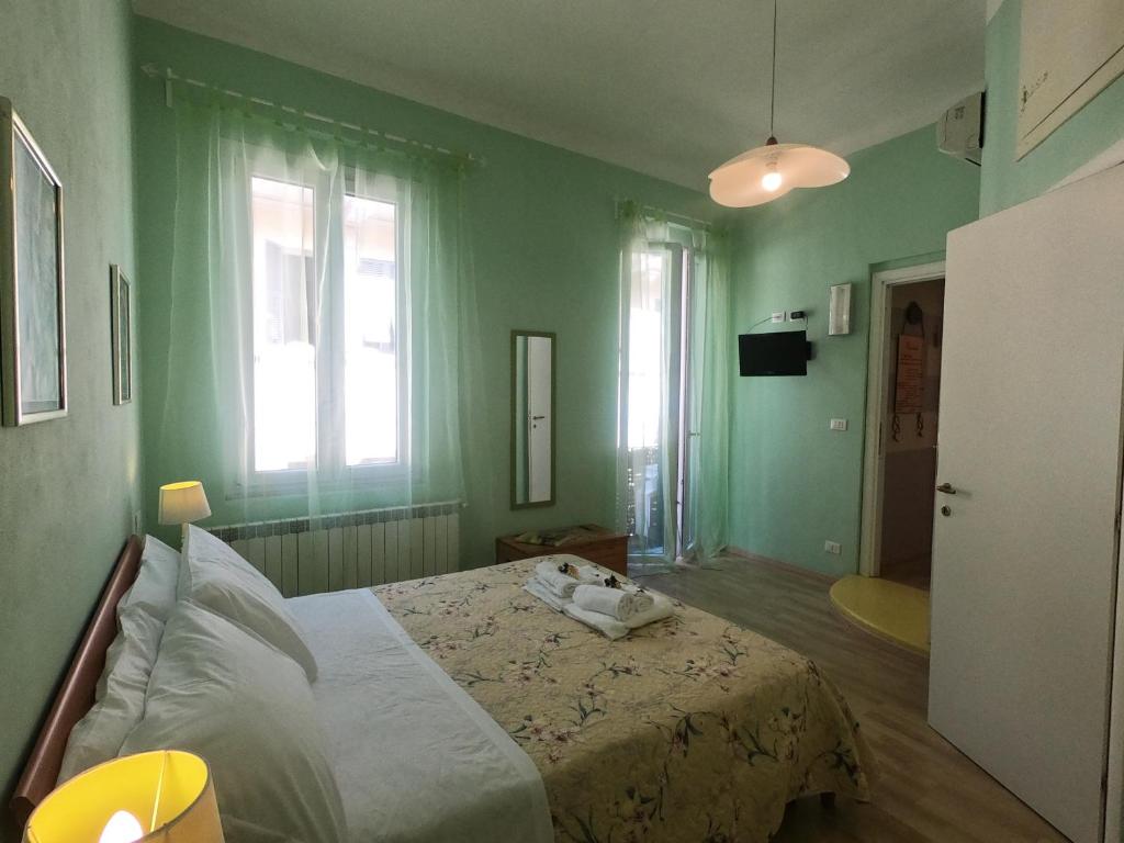ein grünes Schlafzimmer mit einem Bett und zwei Fenstern in der Unterkunft Valerie in La Spezia