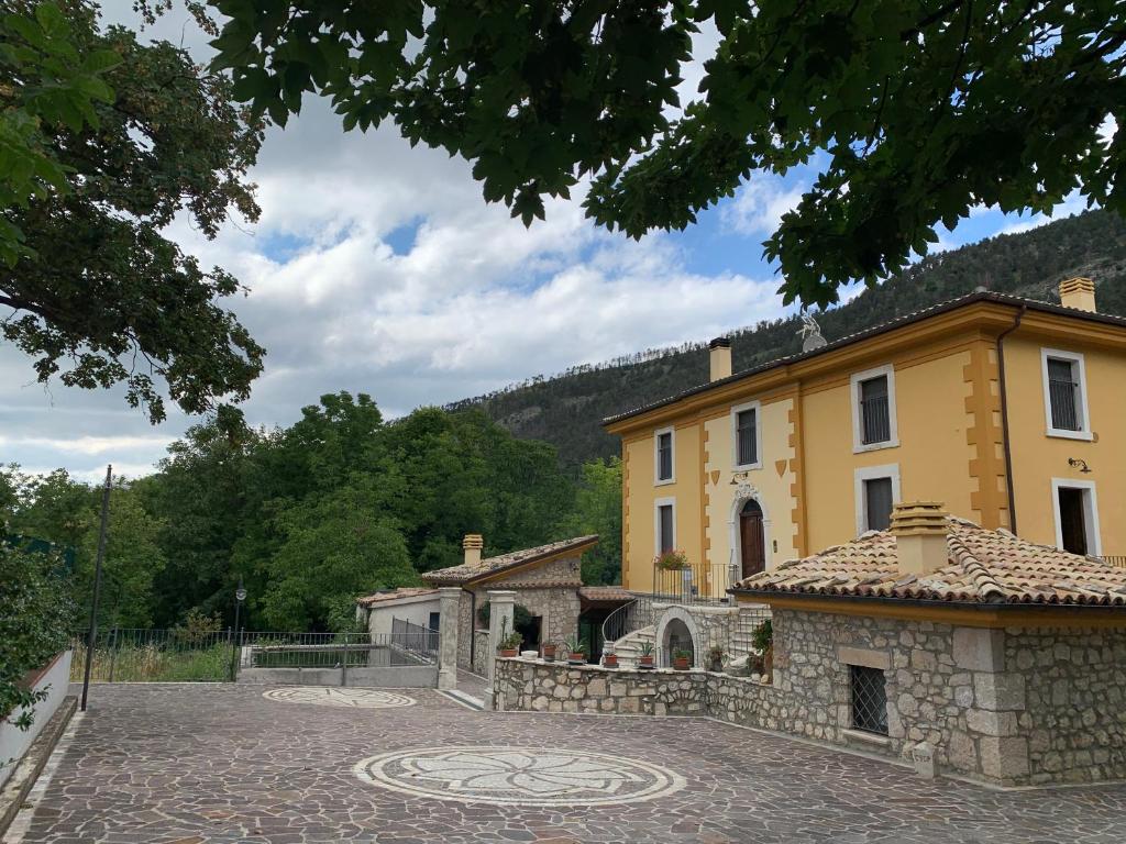 un gran edificio amarillo con un patio de piedra en Casale Alberico en Caramanico Terme