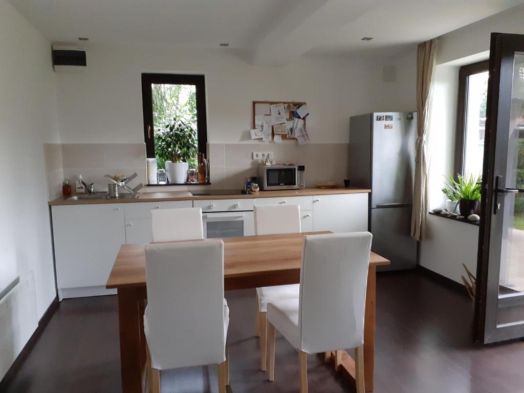 a kitchen with a wooden table and white chairs at Nature apartman in Tata