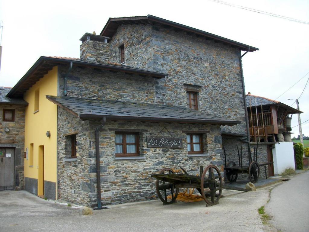 a stone building with a cart in front of it at Casa de Aldea Rural Los Glayus in Luarca