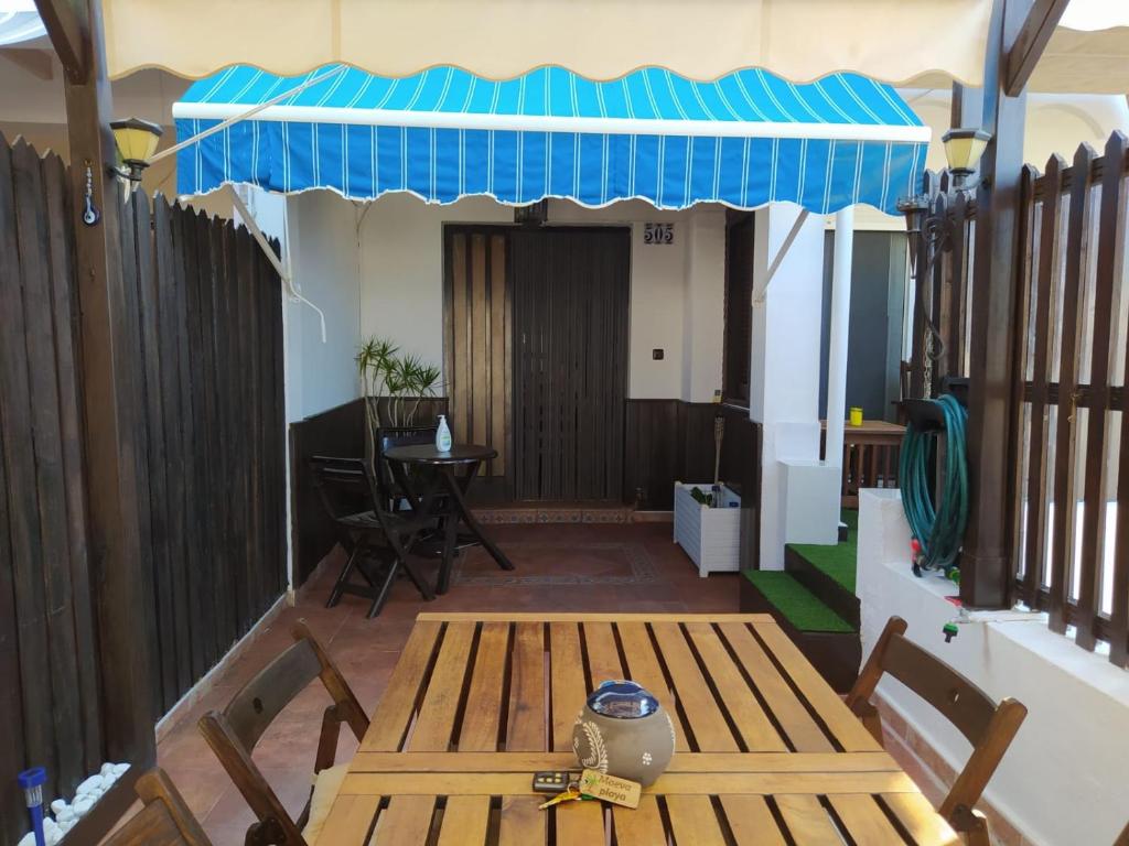 een veranda met een houten bank en een blauwe luifel bij MAEVA PLAYA BUNGALOW in El Campello