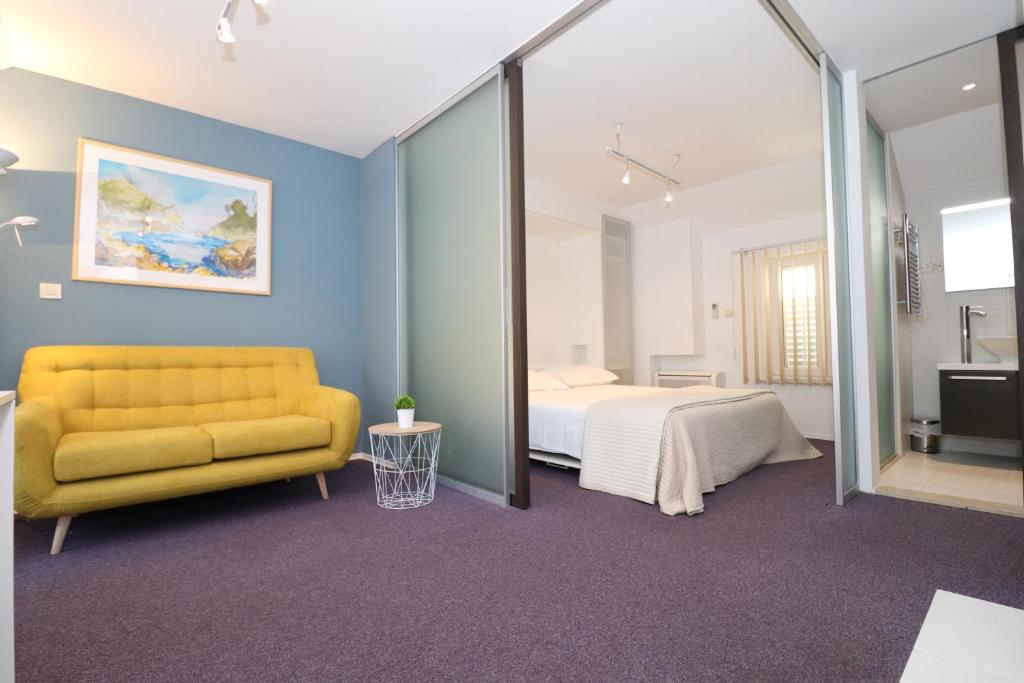 a bedroom with a yellow couch and a bed at Miró Studio Apartments Dubrovnik in Dubrovnik