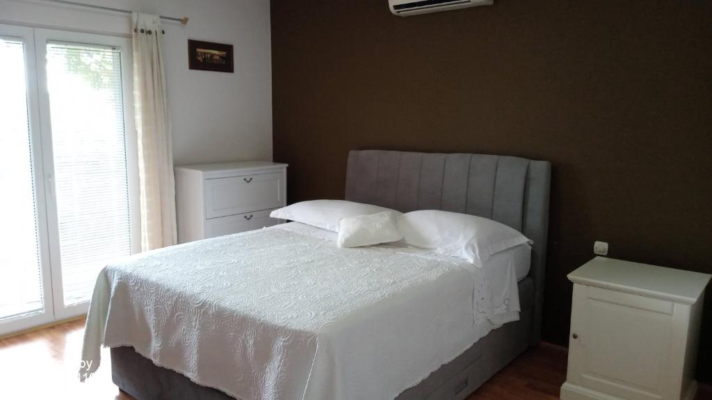 a bedroom with a bed with white sheets and a window at Nera Apartment in Brodarica