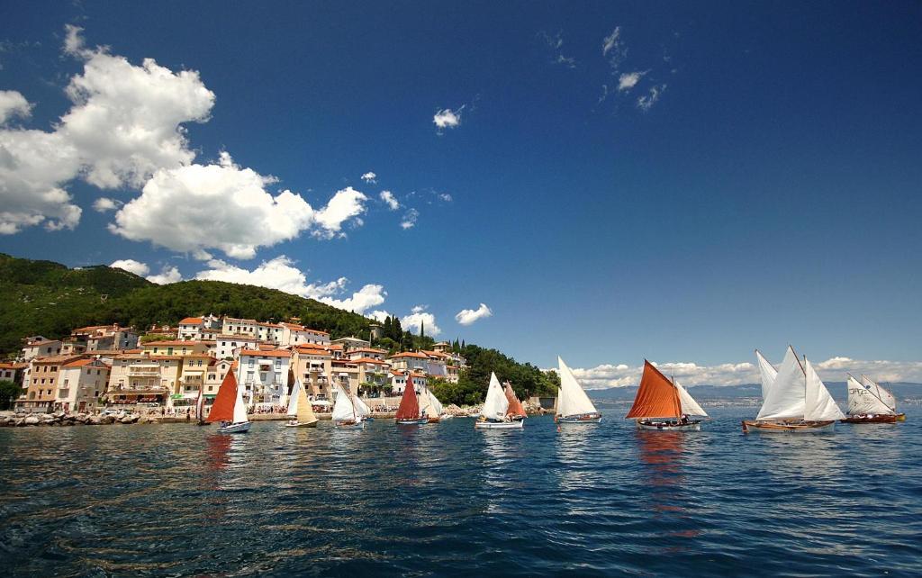 Un grupo de veleros en el agua frente a una ciudad. en Apartman Gržin, en Mošćenička Draga