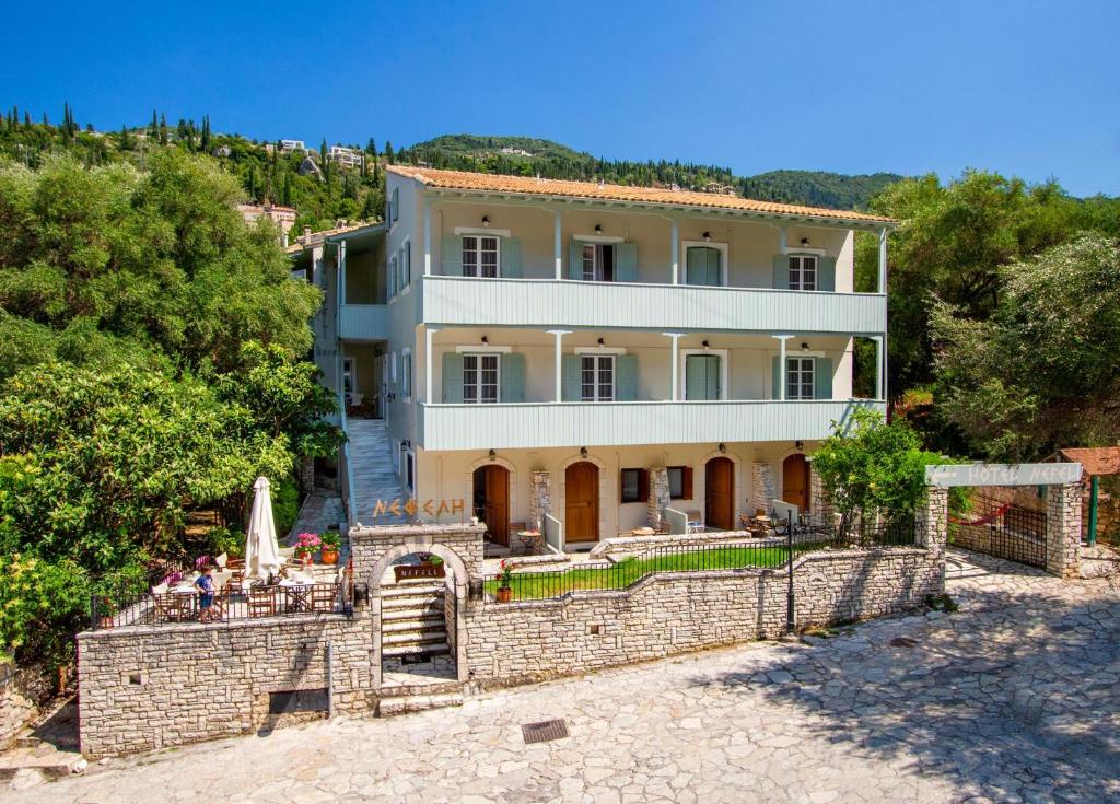 an external view of a house with a stone wall at Nefeli Hotel in Agios Nikitas