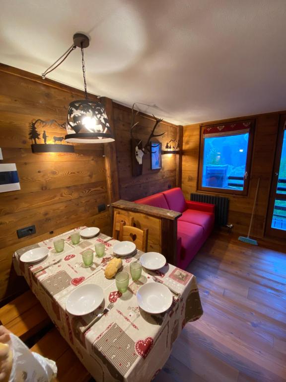 ein Wohnzimmer mit einem Tisch und einem roten Sofa in der Unterkunft Baita delle marmotte CIR n 0012 in Breuil-Cervinia